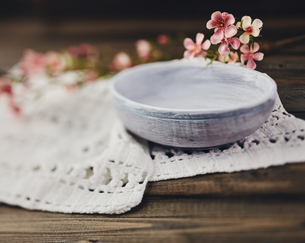 Still life with white ceramic bowl and blossoms on rustic wood table